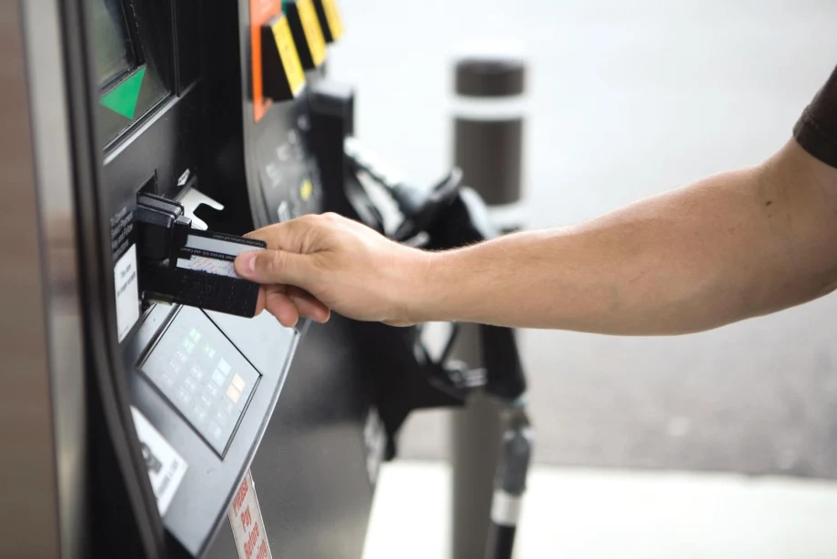 Person inserting a payment card into a fuel pump card reader at a gas station