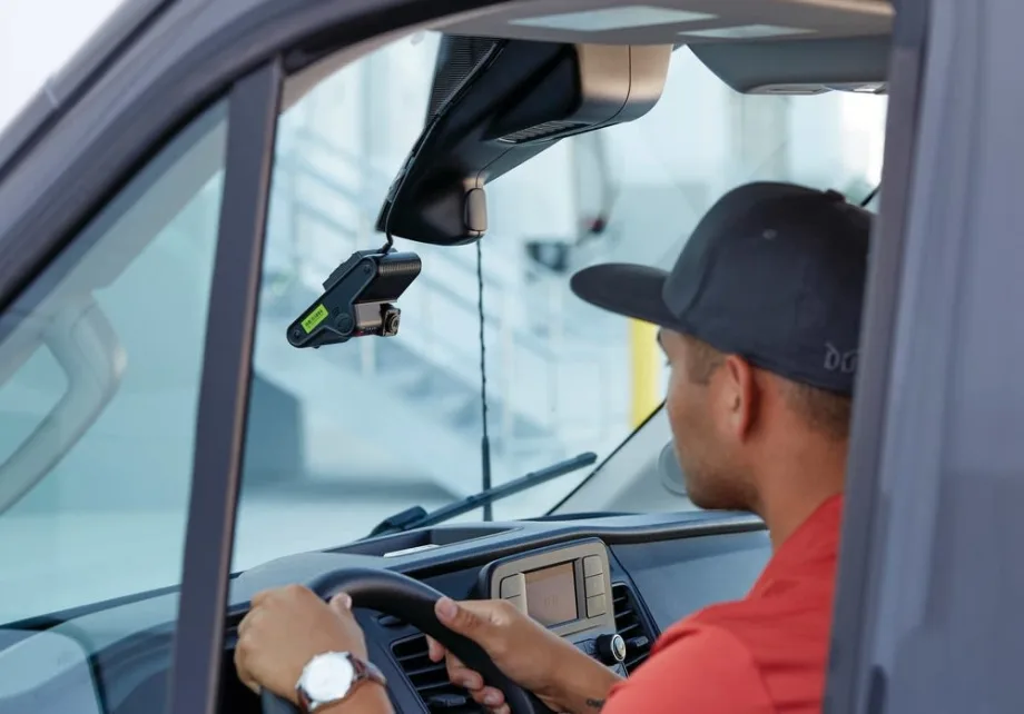 A man in a hat driving in a car with a dashcam overhead