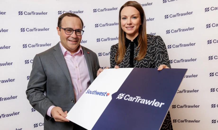 Two execs hold up a sign with Southwest and CarTrawler logos