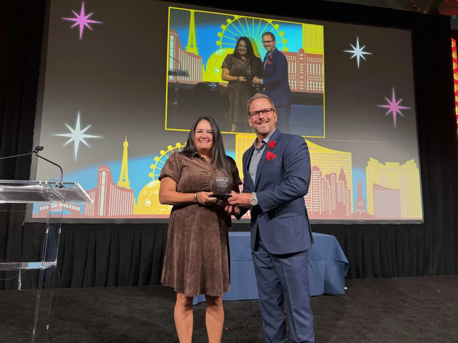 Jamie McKay stands on stage and poses with teh 2026 Fleet Visionary award at AFLA