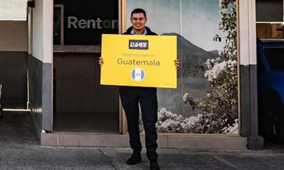Franchisee standing with yellow U-Save branded sign in front of the rental car outlet.