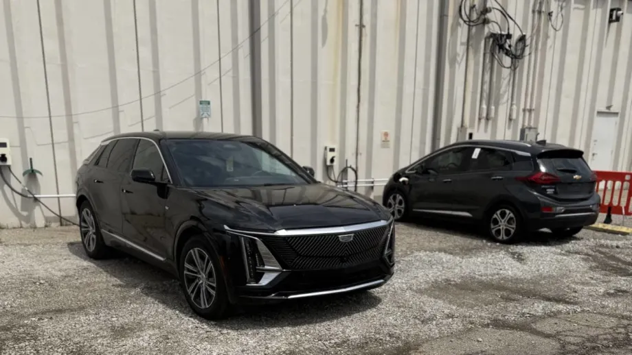 Two EVs charging along an auto auction maintenance building.
