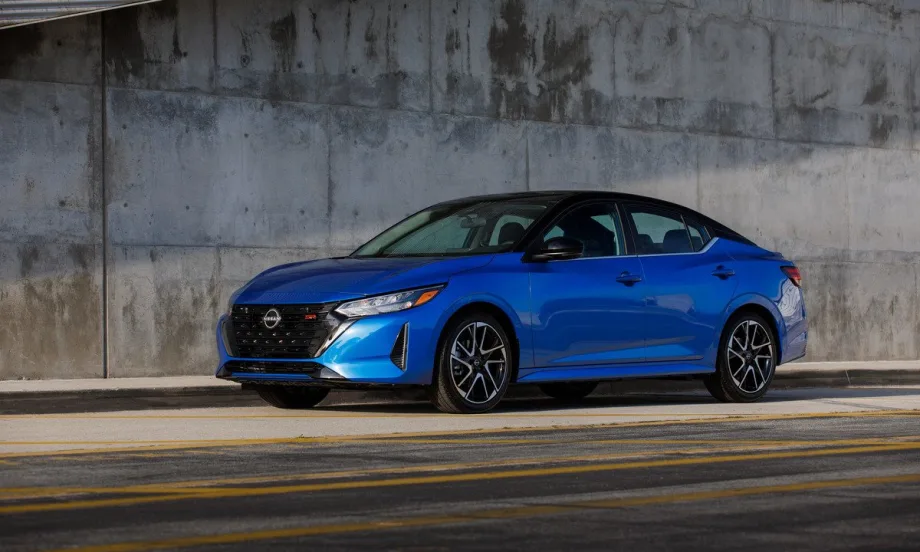A cobalt blue 2025 Nissan Sentra parked on the side of the road underneath an overpass.