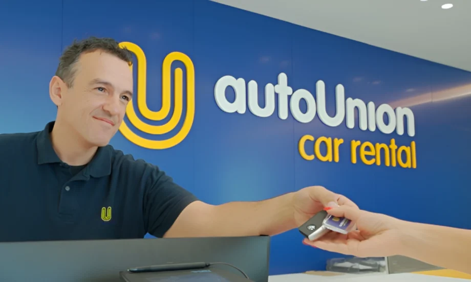 Rental car agent hands over key at AutoUnion Car Rental counter.