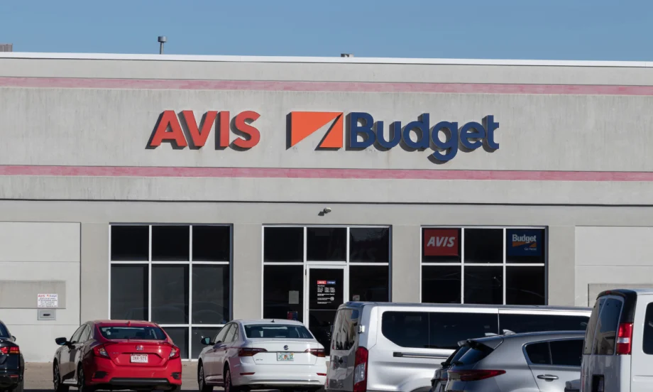 Rental cars lined up in front of an Avis-Budget storefront outlet.