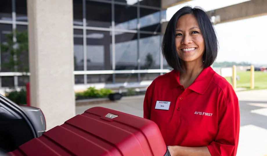 An Avis rep unloads luggage from a rental car as part of first-class service.