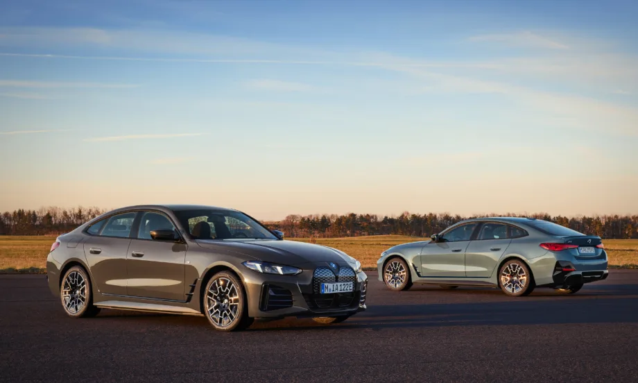 Two BMW i14s are posed on the open road in front of a sunset, with one facing away with a view of the back.