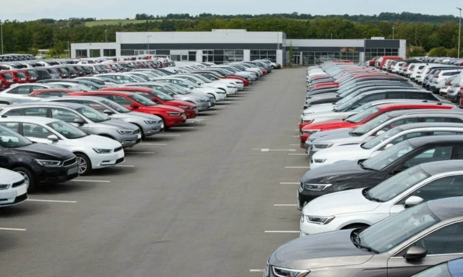 New vehicles lined up in a large parking lot at a dealership in west-central Brazil, with the modern dealership building in the background.