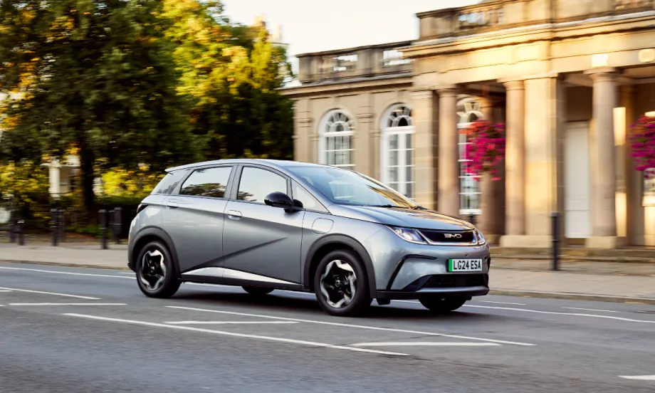 Photo of a gray BYD Dolphin sub-compact electric vehicle in front of a columned historic building.
