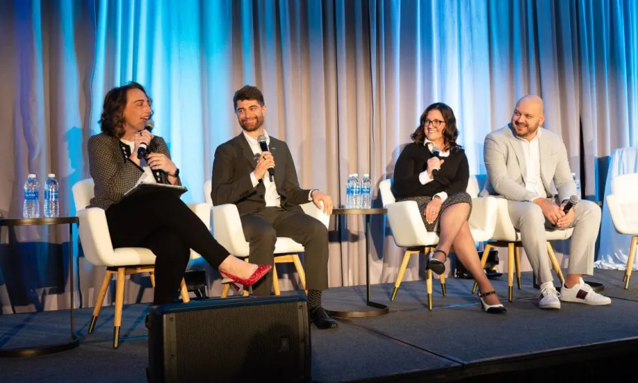 Panelists on stage in front of curtain during conference.
