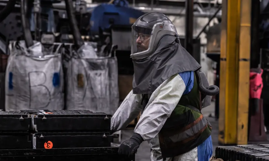 Technician handling electric vehicle battery components in a recycling facility as Cox Automotive expands EV battery processing and material recovery operations.
