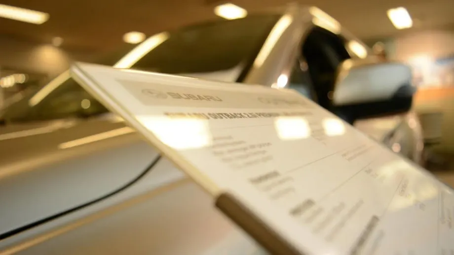 Sales board in front of a car inside a dealership showroom floor.