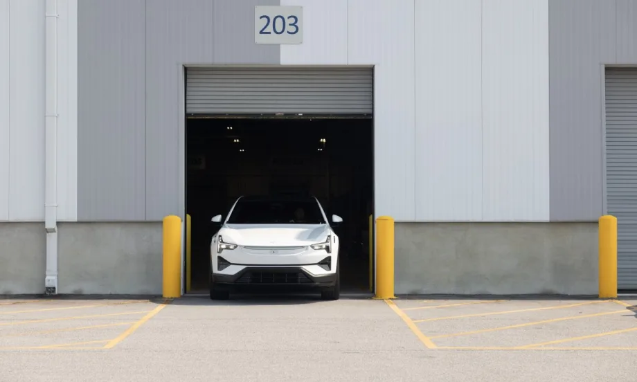 An image of the front end of a white Polestar 3 parking within the open frame of a commercial garage door.