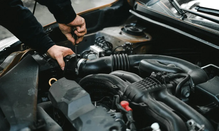 The hands of an auto mechanic checking the engine of a car.