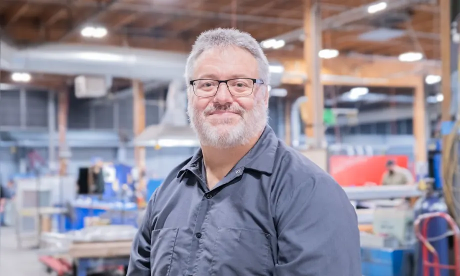 A professional portrait of Bruce Birdsell in a workshop/warehouse.