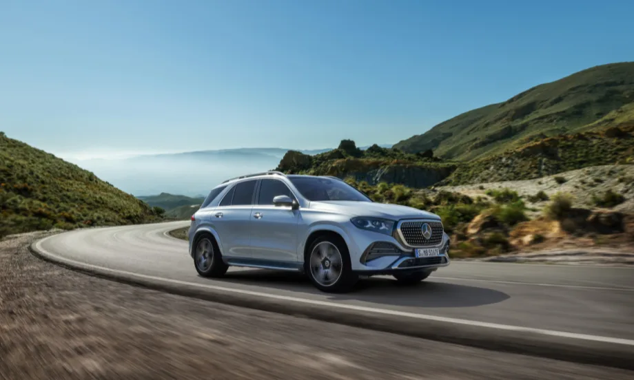 Silver Mercedes-Benz GLE SUV driving on a winding mountain road, showcasing updated exterior design and performance in a scenic landscape.