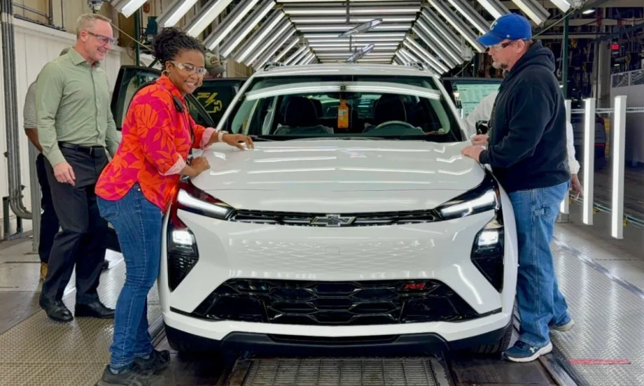 Three people stand next to a Chevy Equinox.