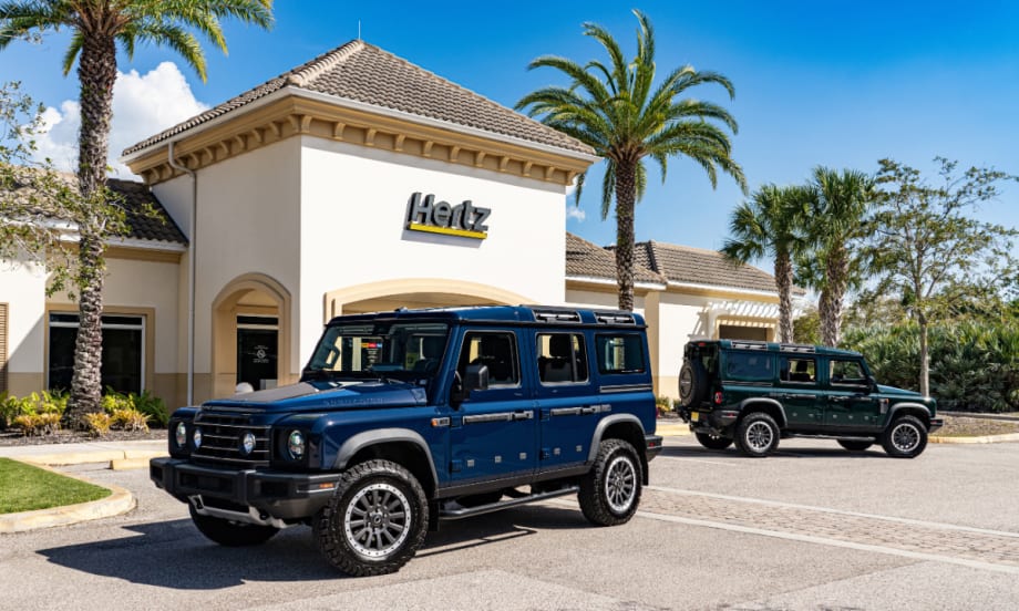Photos of two black INEOS Grenadier 4x4 vehicles in front of a Hertz rental car outlet.