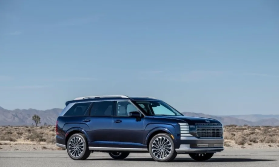 A dark blue full-size SUV parked on a desert road, with sleek modern styling, large alloy wheels, and a chrome-accented grille, set against a backdrop of dry desert landscape.