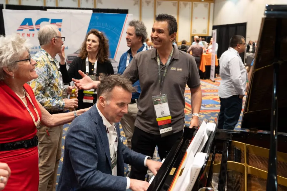 Attendee playing piano on exhibit floor and entertaining guests.