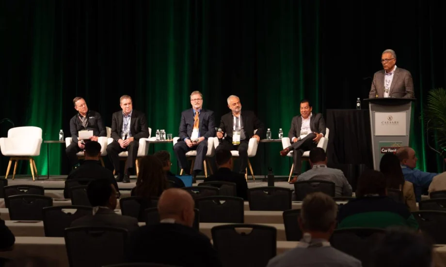 Five panelists sitting in white chairs and a moderator at the podium on stage at ICRS
