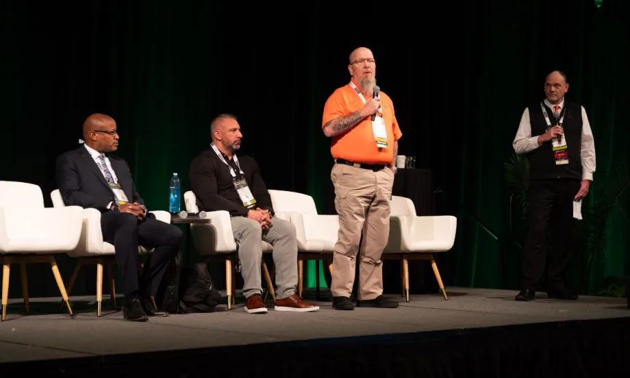 Panelists seated and standing on stage at conference.