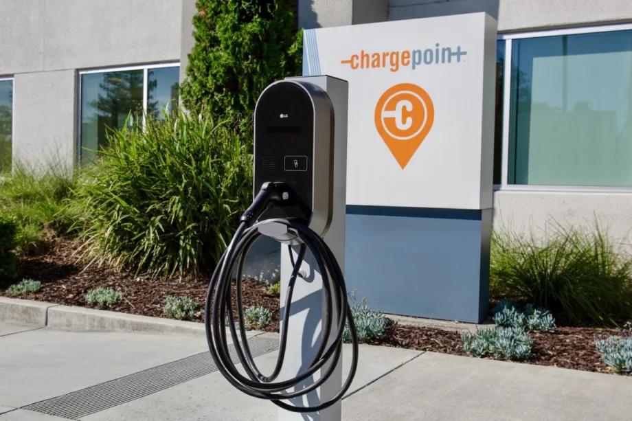 An outdoor LG electric vehicle charging station in front of a ChargePoint company sign and office building.