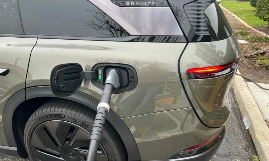 A Lucid Gravity parked at a charging station with a charging cord inserted into the port.