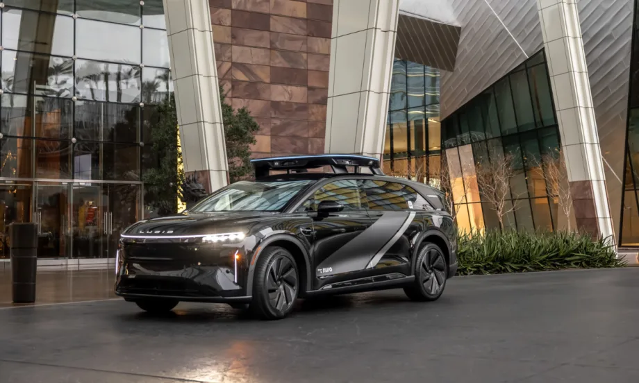 Lucid electric vehicle equipped with rooftop sensors parked outside a modern building, representing expanded partnership with Uber for future robotaxi deployment.