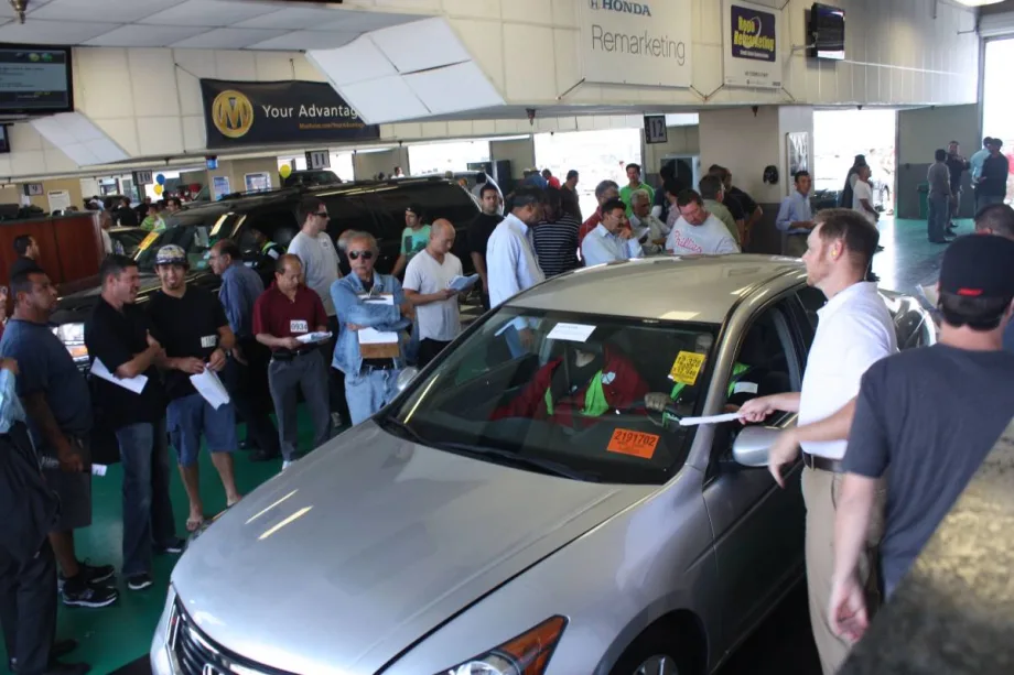 Buyers and sellers gather around a vehicle at a live in-lane auction.