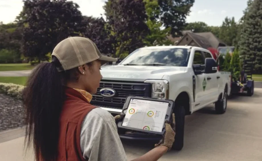 A worker using an ipad standing in front of a work truck.