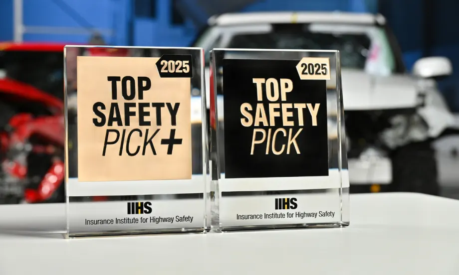 Close up image of Top Safety Pick+ and Top Safety Pick awards in front of crash test cars.