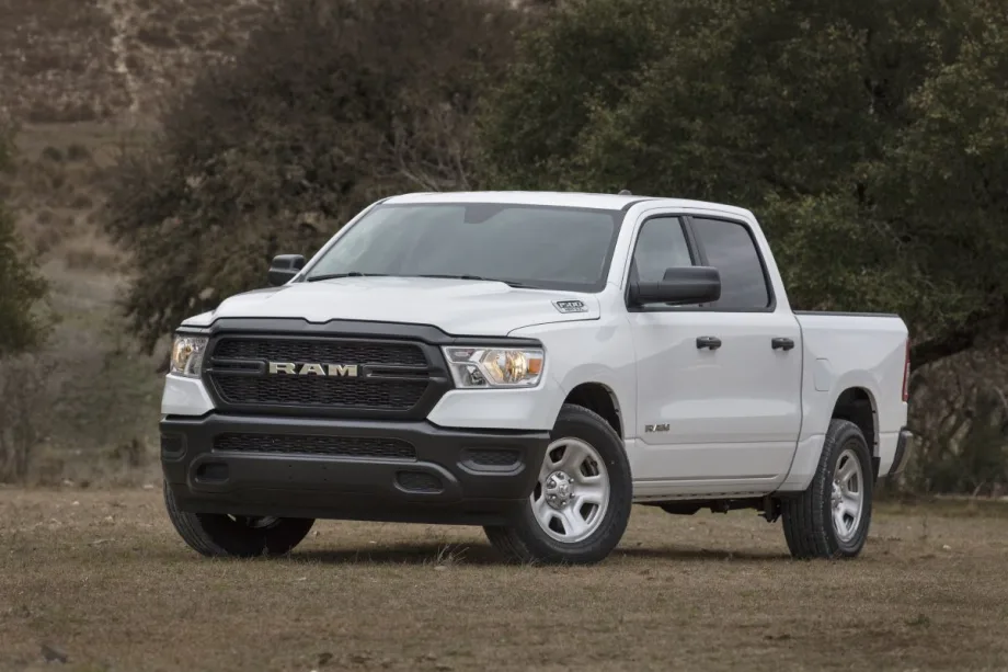 White RAM truck in front of foliage.