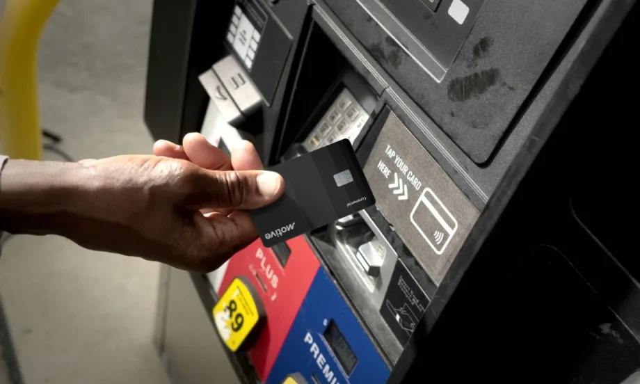 A hand holding the black Motive card for fleets is about to insert the card at a gas pump.