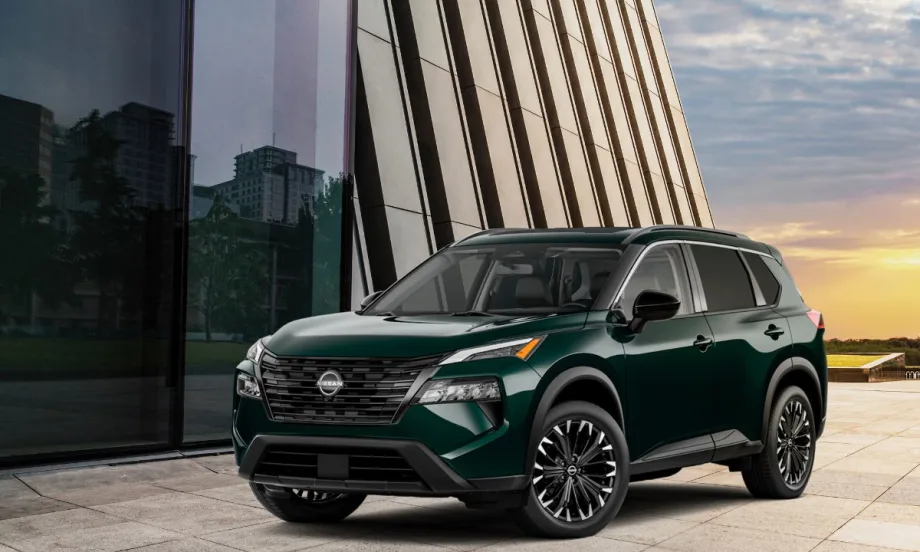 Dark colored Nissan SUV parked in front of modern glass and stone buildings at sunset.