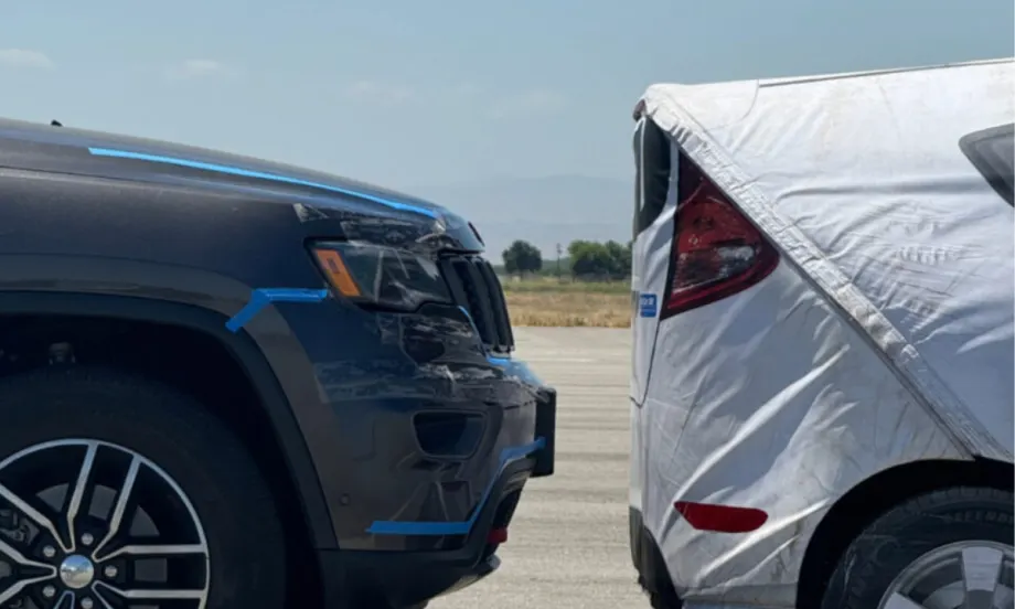 An image of a crash test with a gray car stopping right before hitting a white test car.