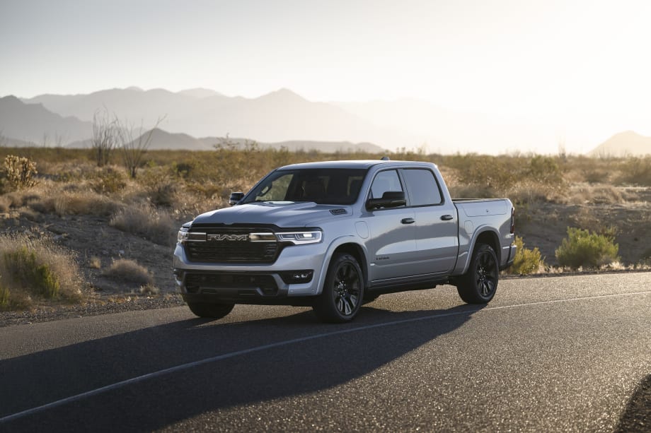 “Silver Ram pickup truck parked on a desert highway with mountains in the background at sunset.”