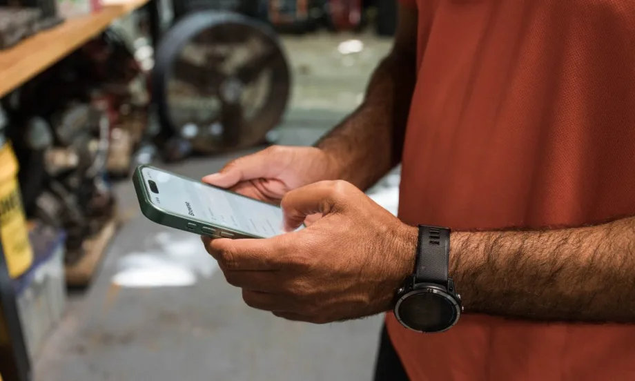 Person holds phone in both hands to read safety analytics for fleets.