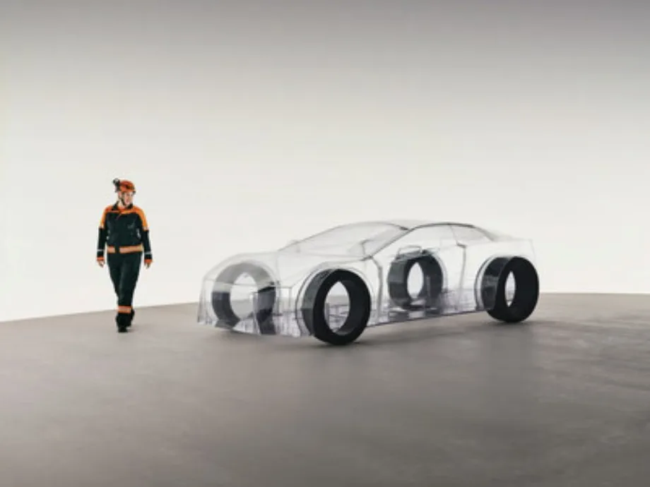 A Sandvik engineer stands beside the transparent eNimon installation, a full-scale model of an electric car made without any metals or minerals, symbolizing the importance of mining for EV production.