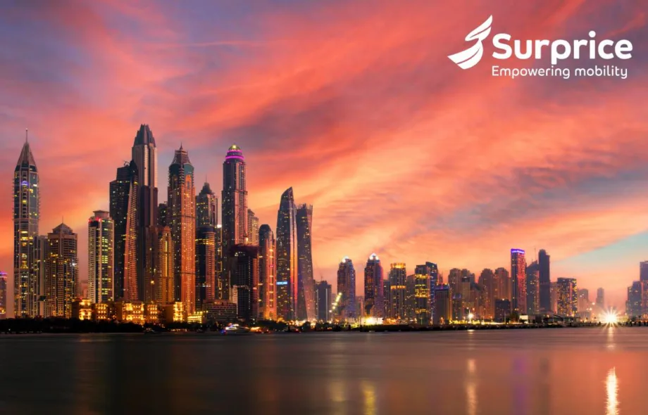 Glittering waterfront Dubai skyline against a reddish sunset sky.