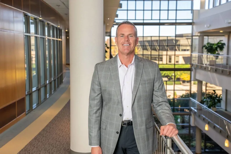 TSD's CEO posed in the atrium of a large modern office building.