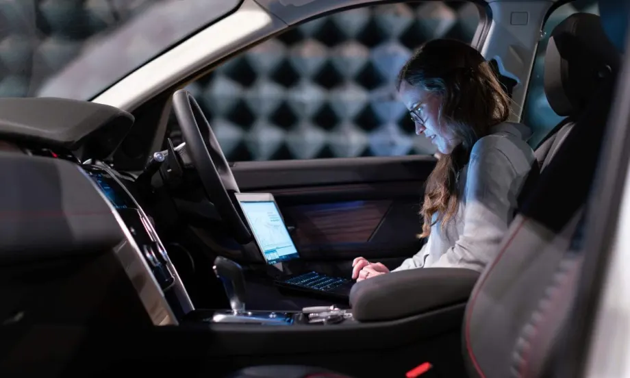Data analyst looking at computer screen while seated in front of vehicle.