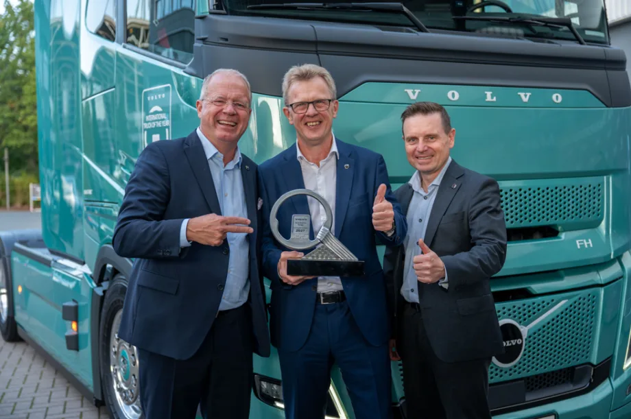 Three Volvo leaders stand in front of a turquoise Volva truck