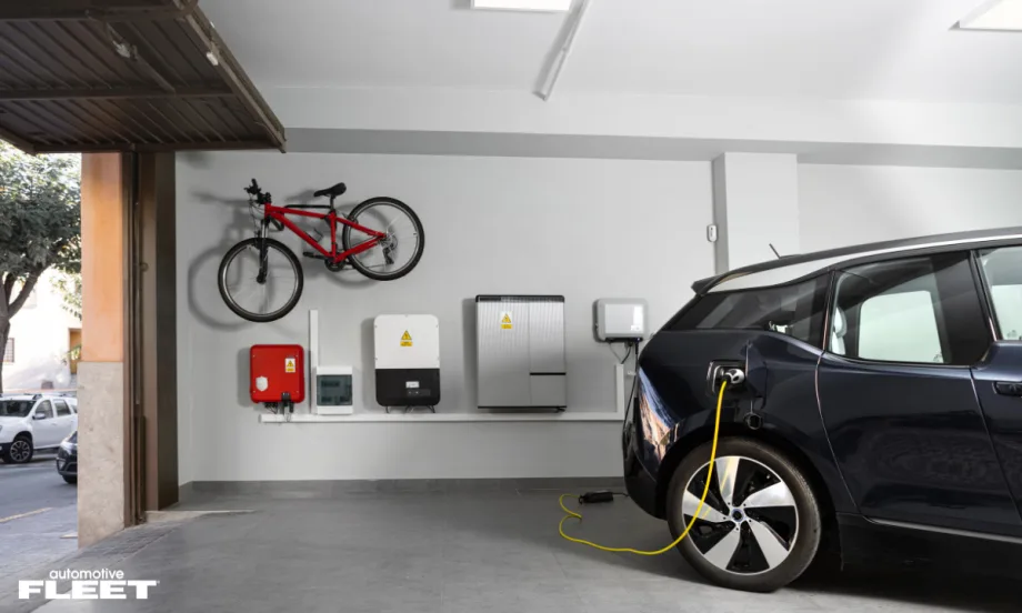 Electric vehicle charging in a home garage with wall-mounted charging and energy systems, illustrating WEX EV At-Home fraud protection and fleet charging verification technology.