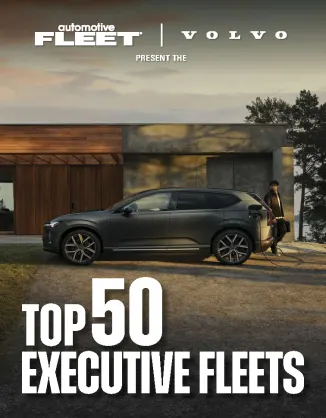 A shot of a Volvo electric vehicle with a man charging it in front of a residence.